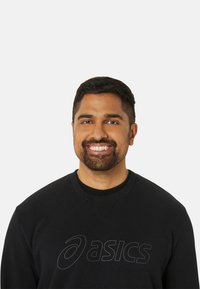 Sweatshirt noir avec un col rond et un logo texturé dans une teinte plus claire. Le tissu semble doux avec une coupe décontractée.