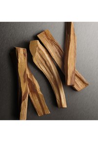 Naturliga träpinnar med släta, kurviga kanter som visar ljusa och mörka träådringar mot en metallgrå bakgrund.