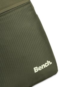 Olijfgroen tas met een gestructureerd hexagonaal patroon, voorzien van een ritssluiting aan de bovenkant en een wit "Bench" logo aan de voorkant.