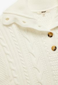 Witte gebreide sweater met een kabelbrei ontwerp, geribbelde kraag en twee bruine knopen. Textuurstof met een gezellige uitstraling.