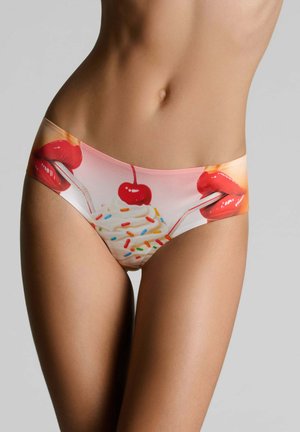 Femme portant des sous-vêtements imprimés de lèvres rouges sirotant à travers des pailles un dessert à la crème fouettée garni d'une cerise et de vermicelles.