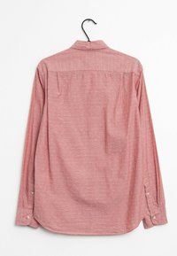 Chemise à manches longues de couleur rose pâle avec un motif discret de pois blancs, dotée d'un col standard et de poignets boutonnés, fabriquée en tissu léger.
