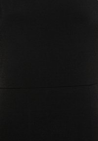 Vestido preto feito de um tecido suave e elástico. Apresenta um design sem costuras e uma costura horizontal subtil na linha da cintura.