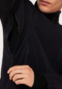 Black jacket featuring multiple zippers, a high collar, and textured fabric. Showcases a fitted design with elastic cuffs and pockets.