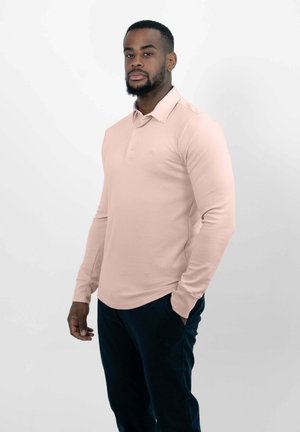 Lange mouwen roze polo met een kraag, voorzien van een logo op de borst, gecombineerd met marineblauwe broek. Glad textuur, aansluitende pasvorm.