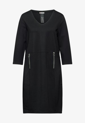 Musta mekko pehmeästä kankaasta, jossa on V-kaula-aukko, kolmanneksen hihat ja tiukka muotoilu, jossa on kaksi vetoketjullista taskua.