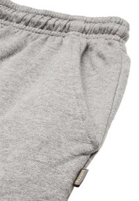 Graue Strick-Sweatpants mit elastischem Bund, Seitentasche und einem kleinen Markenetikett nahe dem Saum. Strukturierte Details des Stoffes sind sichtbar.