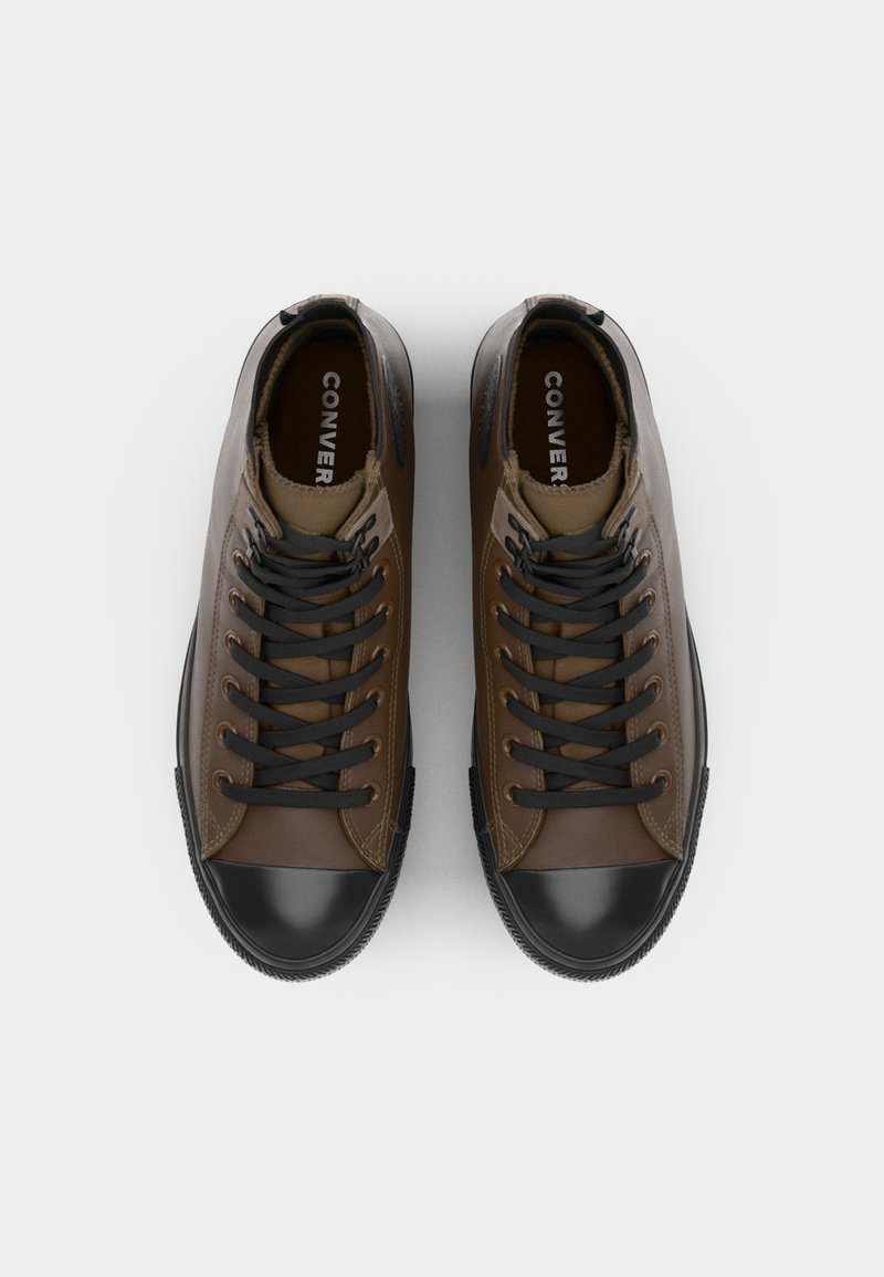 Sneaker alte marroni con puntale in gomma nera e dettagli neri, dotate di lacci neri, pelle testurizzata e branding stampato sulla linguetta.