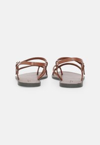 Sandali in pelle marrone con cinturini sottili, suola grigia piatta e design minimalista. Presentano una fibbia regolabile per una vestibilità adatta.