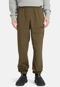 Cargo byxor i olivgrön, med elastiskt midjeband, avsmalnande ärmar och en sidficka. Tillverkade av ett lätt, slätt tyg.