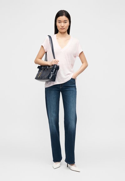 Tricou roz cu decolteu în V, blugi albaștri, drepti, și pantofi cu toc alb cu vârf ascuțit. Geantă neagră cu detaliu de curea și accent de breloc.