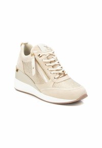 Zapatillas deportivas con cuña en color beige, confeccionadas con materiales de malla y ante, que cuentan con un zipper lateral, cordones en la parte delantera y detalles dorados en el talón y la herrajería.