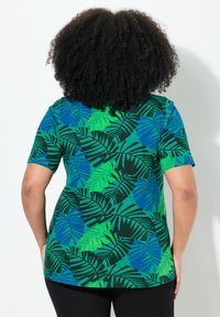 Grön t-shirt med kort ärm som har ett stort lövtryck i nyanser av blått och grönt, med en avslappnad passform och rundad nederkant.