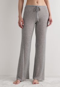 Světle šedé žebrované volné kalhoty s pasem na zavazování a rozšířenými nohavicemi, vyrobené z měkké, texturované látky s uvolněným střihem.