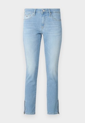 Jeans de denim azul claro com um corte justo, apresentando fechos de correr laterais nas bainhas e um design clássico de cinco bolsos com um desbotado sutil.