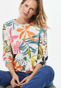 Bluse mit floralem Muster in Weiß mit bunten Blumen- und Blätternmustern. Gerippte Textur, runder Ausschnitt und Dreiviertelärmel.