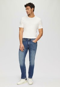 Witte kortemouwt-shirt gecombineerd met lichtblauwe skinny jeans en witte sneakers, met een klassieke pasvorm en een gladde textuur.