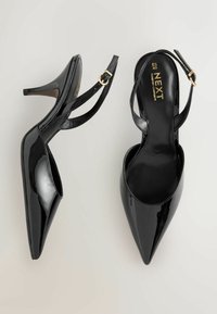 Melni lakādas augstpapēžu apavi ar smailu purngalu, atvērtu aizmuguri un regulējamu potītes siksniņu; ar zelta toņa sprādzes dekoru.