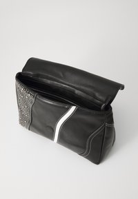 Black leather bag with a white accent stripe, textured studded side, zip closure, and a rounded flap. Interior is spacious and lined.