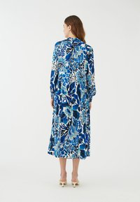 Blumiges Maxikleid mit blauen Tönen, langen Ärmeln, einer Bindeschleife am Hals und einer lockeren Passform mit einem Saum, der bis zur Mitte der Waden reicht.