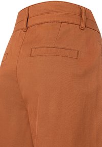 Braune Baumwollhose mit geradem Schnitt, glatter Textur und zwei Gesäßtaschen, mit ordentlich genähten Nähten und einem sauberen Finish.