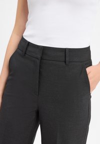 Donkergrijze op maat gemaakte broeken van een gladde stof. Heeft een middelhoge taille, zijzakken en een strakke, elegante uitstraling.