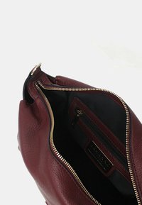 Borsa in pelle bordeaux con chiusura a zip, caratterizzata da una superficie testurizzata, una tasca interna e finiture in tono oro.