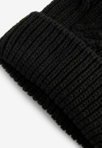 Schwarze gestrickte Mütze mit geripptem Muster, aus dickem Garn gefertigt. Der umschlagbare Bund verleiht dem Gesamtdesign eine besondere Note.