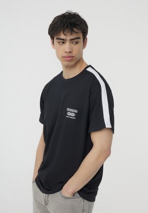 T-shirt nera a maniche corte con una striscia bianca sulla spalla e un logo sul petto. Il tessuto sembra liscio e leggero.