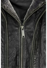 Chaqueta de cuero negra con un suave cuello gris, doble cremallera plateada y un acabado texturizado que resalta la apariencia del cuero desgastado.