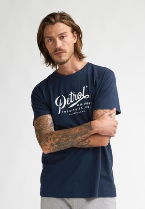 T-shirt en coton bleu marine avec un imprimé graphique blanc portant le texte "Petrol Industries Co." et un col rond.