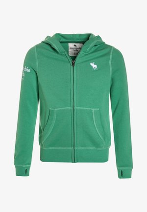 Veste à zip verte avec une poche kangourou, des bords-côtes au niveau des poignets et un logo de morse blanc sur la poitrine et la manche. Matériau doux en mélange de coton.