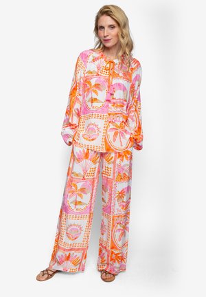 Dwuczęściowy strój składający się z bluzki z długim rękawem i spodni o szerokich nogawkach, wykonany z lekkiego materiału z żywym, różowo-pomarańczowym tropikalnym wzorem.