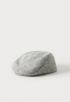 Casquette plate en laine gris clair avec des lignes de couture visibles sur un fond blanc uni.