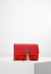 Borsa a tracolla rossa con texture e catena dorata. Presenta una chiusura a pattina con hardware metallico e un accento a frange. Forma rettangolare.