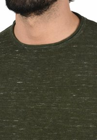 Olijfgroen gebreid T-shirt met een ronde halslijn, met een gestructureerde stof met lichtere vlekken en een ontspannen pasvorm.