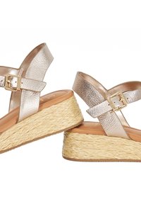 Wedge sandals with metallic rose gold leather straps and gold buckles, featuring braided natural fiber platform soles and tan cushioned footbeds.