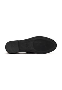 Suola nera di scarpa con gomma testurizzata e aree lisce. Presenta un logo impresso discreto e cuciture lungo il bordo. Superficie uniforme.