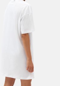 T-shirt oversize en coton blanc avec des manches courtes, un col rond et une texture lisse, montré de dos avec une coupe décontractée.