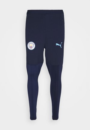Pantalon d'entraînement de football de Manchester City bleu marine avec logo Puma sur la cuisse droite et écusson du club sur la cuisse gauche.
