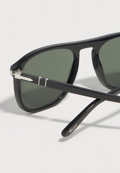 Μαύρα ορθογώνια γυαλιά ηλίου με σκουρόχρωμους πράσινους φακούς και ασημένια μεταλλική λεπτομέρεια σε σχήμα βέλους στο πλαϊνό μπράτσο με το λογότυπο "Persol".