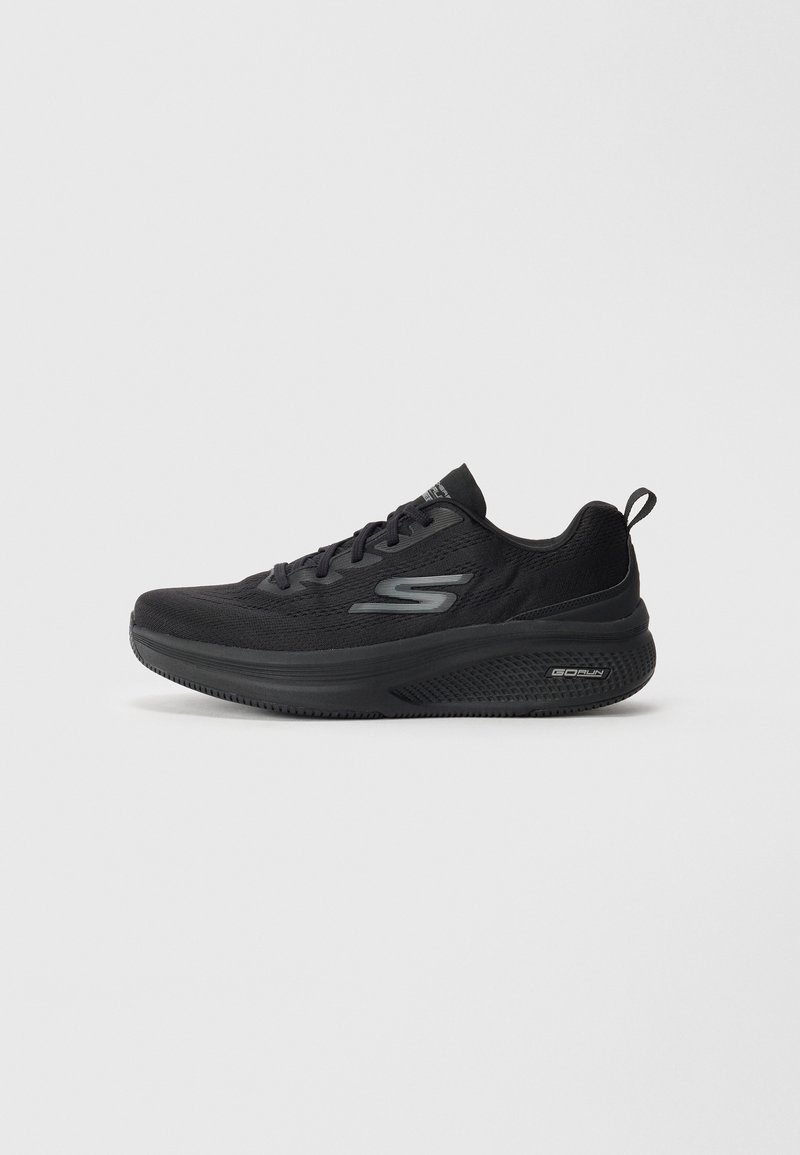 Basket de sport noire avec lacets, semelle rembourrée, logo de marque sur le côté et languette au talon sur fond clair uni.