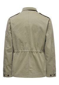 Giacca militare verde oliva con vita stretta, colletto piatto e spalline. Realizzata in tessuto leggero con polsini abbottonati.