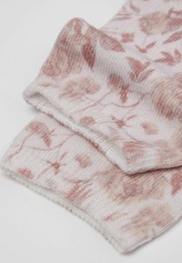 Strikkede sokker i blød pastelrosa med et blomsterdesign i rosé- og beige nuancer. Tekstureret stof med ribbede manchetter og et sømløst design.