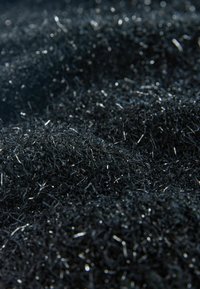 Black synthetic material with fine, reflective strands creating a textured, layered appearance, emphasizing depth and shimmer.