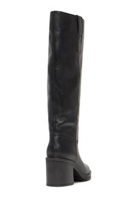 Bottine en cuir noir hauteur genou avec un bout rond, un talon modéré et des coutures verticales sur la tige. Texture lisse avec une finition élégante.