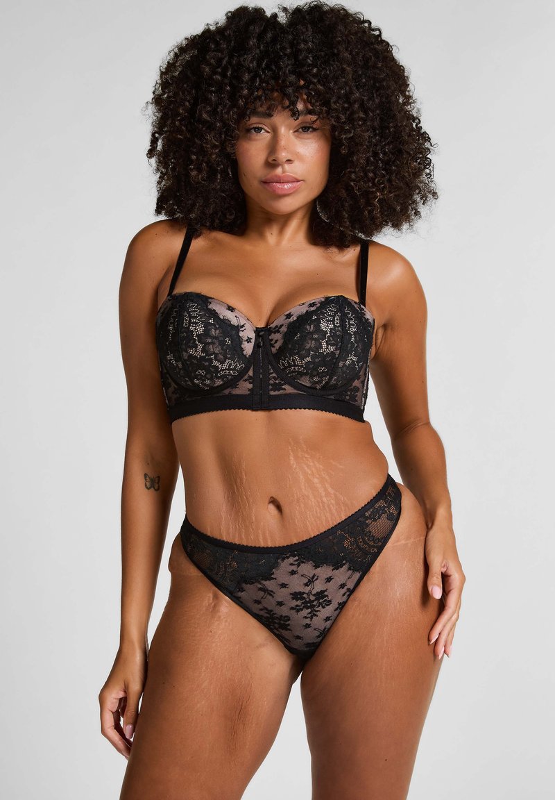 Schwarzes Spitzen-Bralette und passender Tanga mit floralen Mustern, verstellbaren Trägern und halbtransparente Netzdetails.