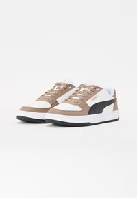 Braune und weiße Sneaker mit einem schwarzen Akzent, die ein glattes Lederobermaterial, eine runde Zehenform und eine traditionelle Schnürung besitzen.
