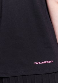 Černé bavlněné tričko s krátkým lemem, hladkou strukturou a růžovým logem "KARL LAGERFELD" v pravém dolním rohu.