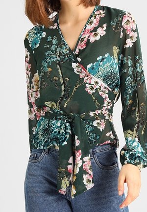 Blumenumhangbluse in Dunkelgrün mit rosa, blauen und weißen Blumen. Lange Ärmel mit einem Bindeband an der Taille; durchsichtiger, leichter Stoff.